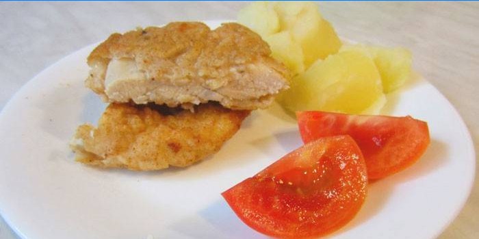 Kana tükelda taignas kartulite ja tomatiga taldrikule