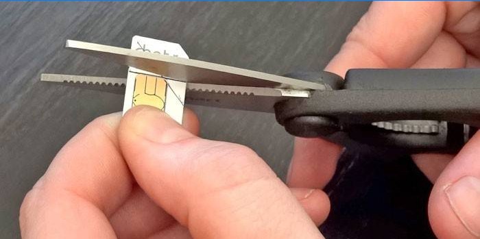 Mees lõikab sim-kaardi vastavalt mustrile kääridega